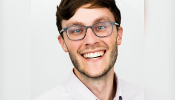 Patient Advocate Austen, a smiling man with short brunette hair and eyeglasses, diagnosed early with PI